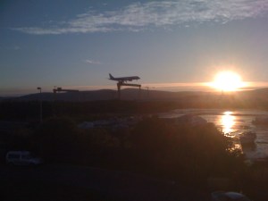 a plane landing against the setting sun